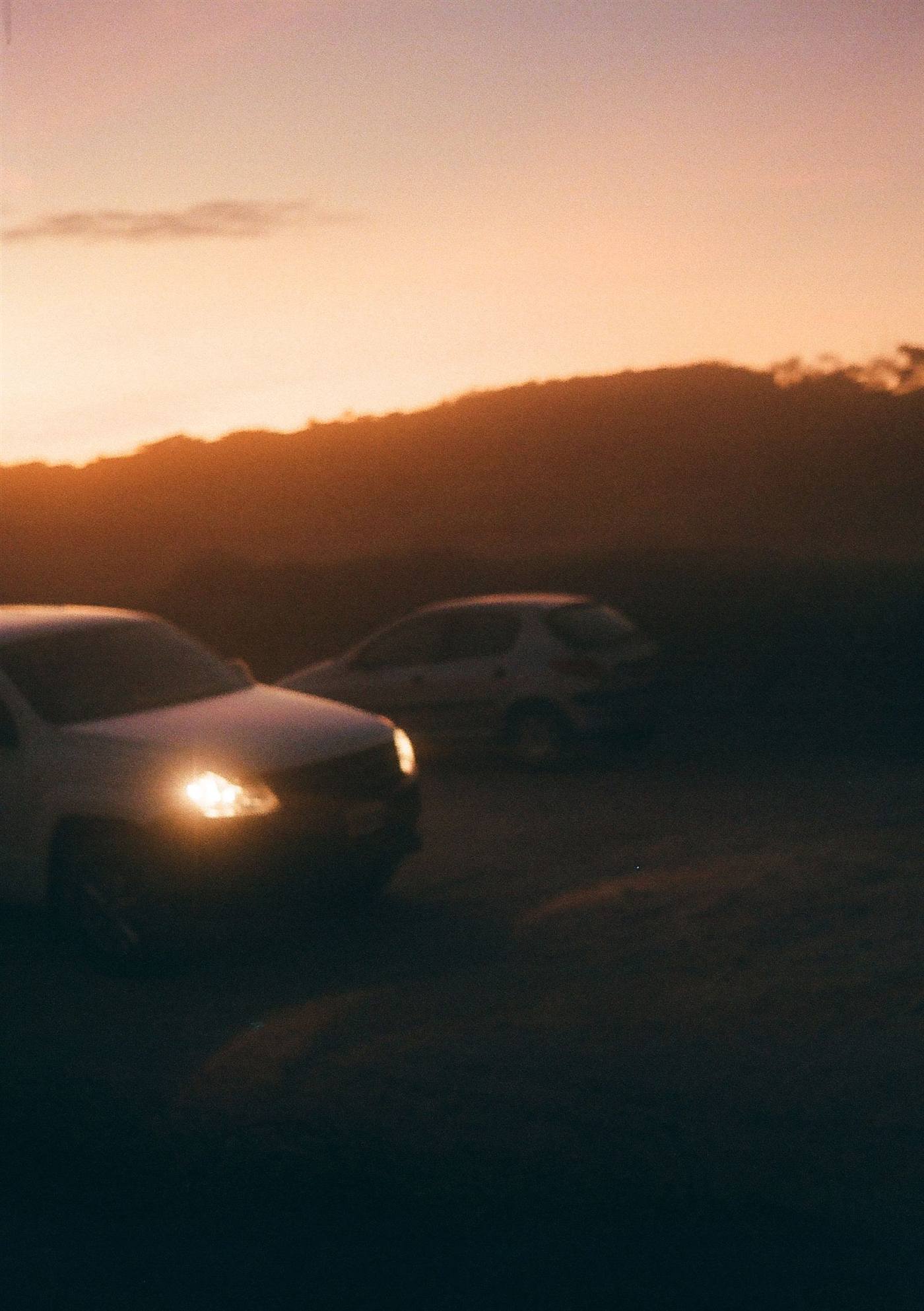 Voiture aux phares allumés au coucher du soleil